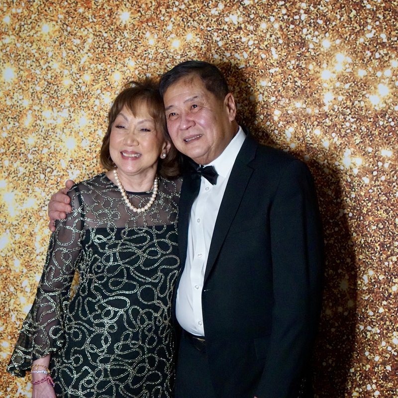 Couple posing at gold glitter backdrop